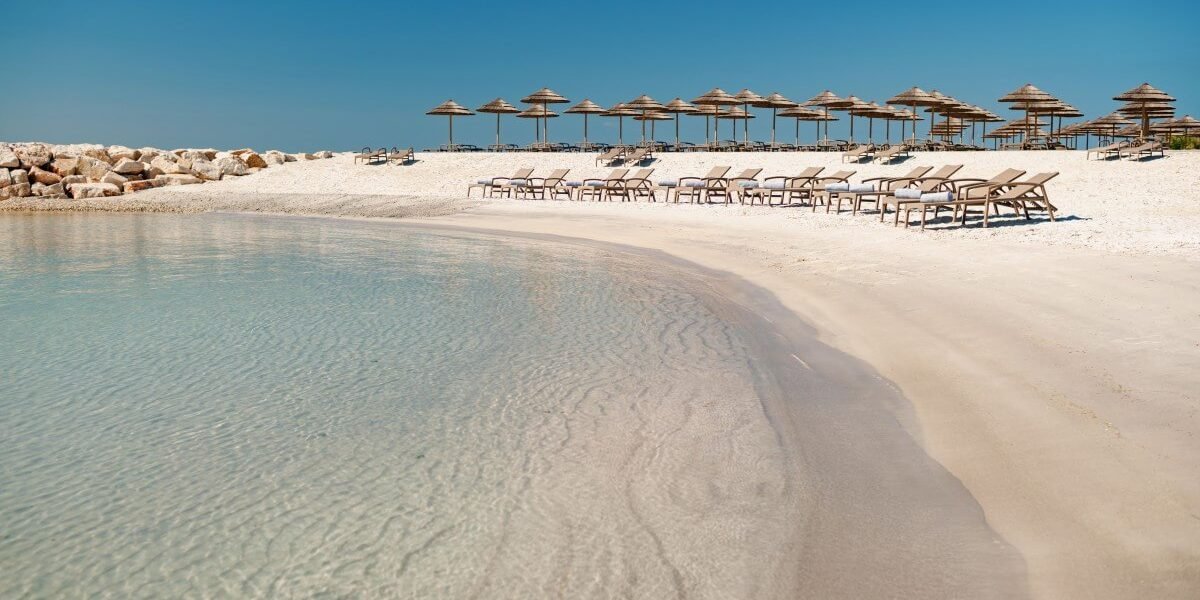 Beach on Sv. Nikola Island near Poreč with sun loungers, parasols, and crystal-clear Adriatic Sea.